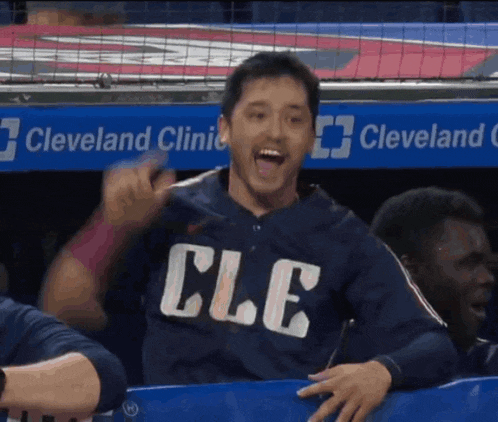 a man wearing a shirt that says cle is sitting in the dugout