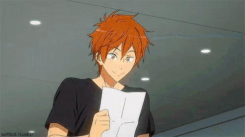 a young boy with red hair is holding a piece of paper in his hand .