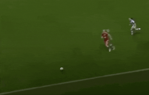 a blurry picture of a soccer game with players on the field and a ball in the middle .