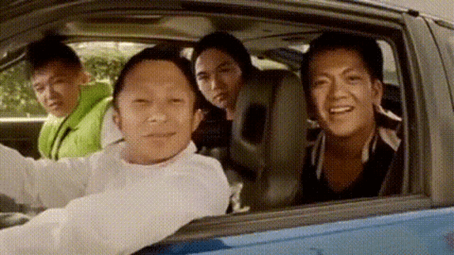 a group of people are sitting in a car looking out the window and smiling .