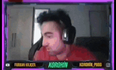 a man wearing headphones and a red shirt is sitting in front of a screen that says korohin .