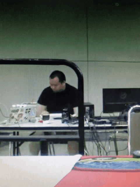 a man is sitting at a table with a laptop and a monitor