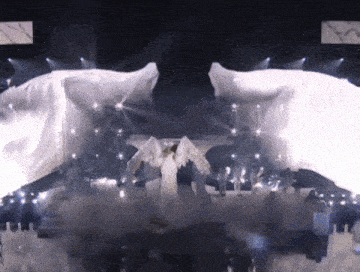 a woman in a white dress with angel wings is standing on a stage
