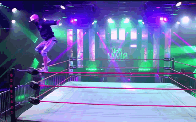 a wrestler is jumping over a rope in a ring