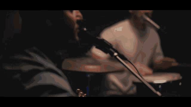 a man singing into a microphone next to a drummer