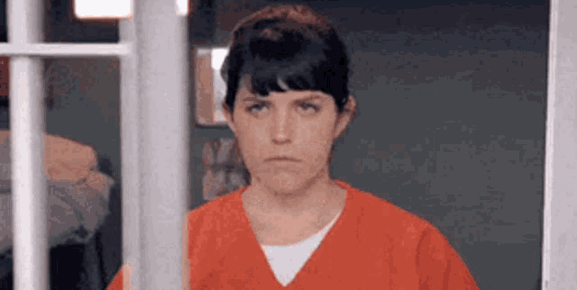 a woman in a jail cell behind bars looking out a window