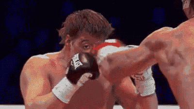a man wearing everlast boxing gloves is hitting another man in the face .