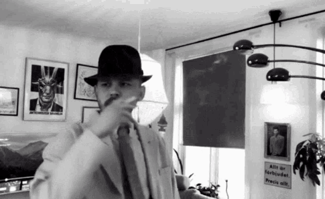 a black and white photo of a man wearing a hat and a suit