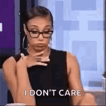 a woman wearing glasses is sitting down and making a funny face .