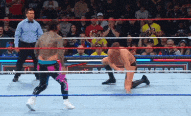 two wrestlers are in a ring with a referee in the background