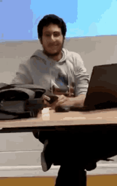 a man is sitting at a desk with a laptop and a cell phone