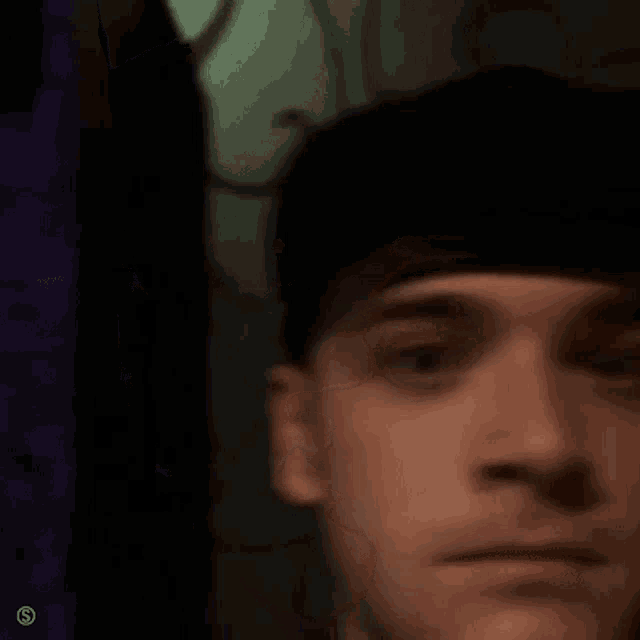 a man wearing a black hat is looking at the camera .