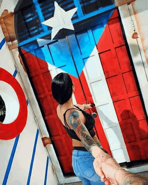 a woman is holding a man 's hand in front of a red white and blue door with a white star on it