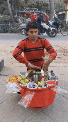 a man in a red sweater is standing in front of a cart full of food
