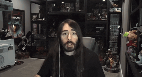 a man with long hair is giving a thumbs down