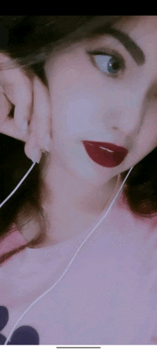 a woman wearing headphones and red lipstick is taking a picture of herself .