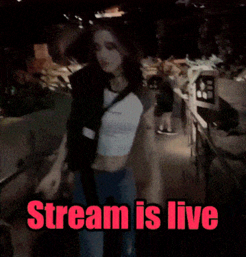 a woman in a white shirt and blue jeans is standing in a dark room with the words stream is live below her