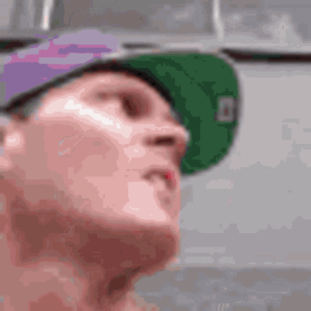 a man wearing a purple hat and a green hat .