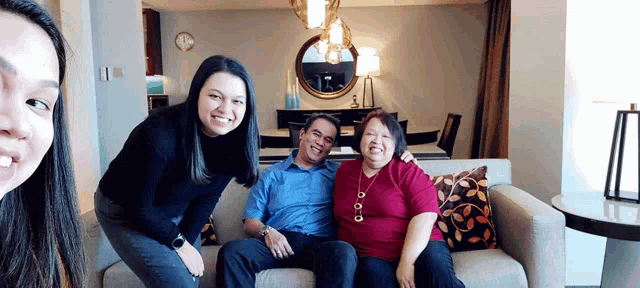 a group of people posing for a picture with a man sitting on a couch