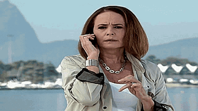 a woman wearing a watch and a necklace is talking on her cell phone