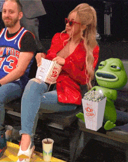 a man wearing a new york jersey sits next to a woman holding a popcorn bucket