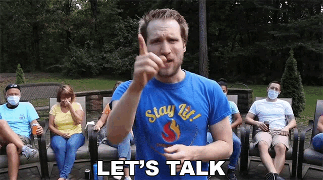 a man wearing a blue shirt that says " stay lit " is talking to a group of people