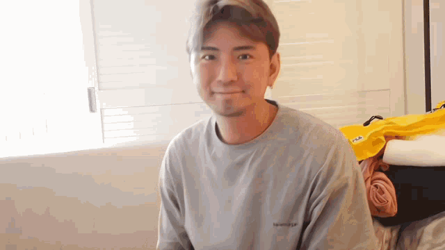 a man wearing a grey balenciaga t-shirt is smiling