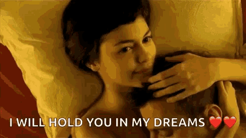 a man and a woman are laying in bed and the woman is kissing the man on the forehead .