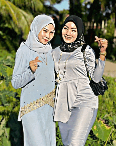 two women are posing for a picture and one is wearing a black hijab