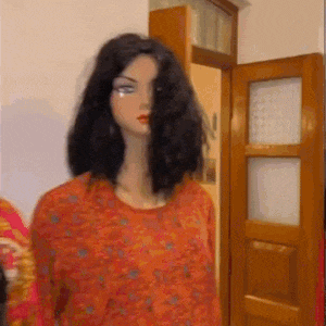 a mannequin with long black hair is wearing an orange top