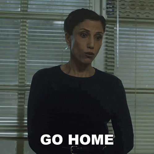 a woman standing in front of a window with the words go home written on her chest