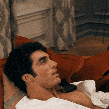 a man laying on a couch with his shirt off and a bow tie