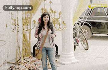 a woman is standing in front of a building with a bicycle parked in front of her .