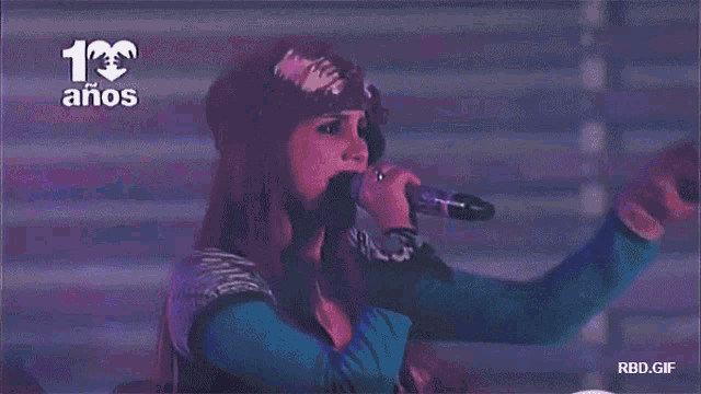 a woman singing into a microphone with the number 13 on the top