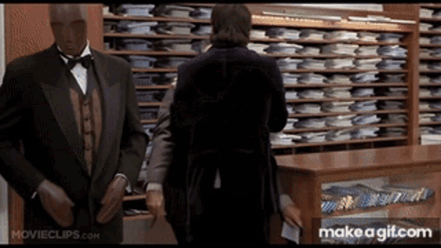 a man in a tuxedo is standing in front of a display case of shirts