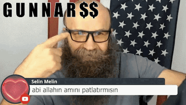 a man with glasses and a beard is standing in front of an american flag