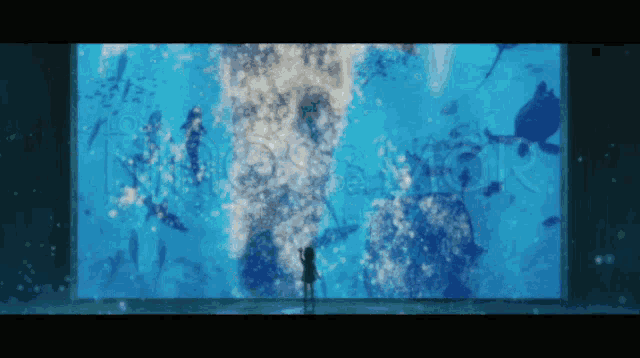 a girl stands in front of a large aquarium with a watermark that says ' a ' on it