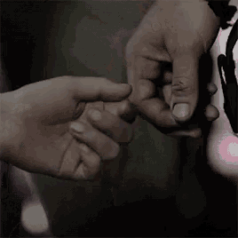 a person is holding another person 's hand in a close up of their hands .