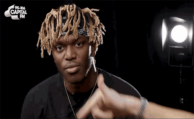a man wearing dreadlocks and a bandana with capital fm on the bottom right