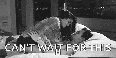 a man and a woman are laying on a bed and kissing .