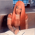 a woman with long orange hair is sitting at a table writing in a notebook with a pen .
