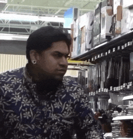 a man in a floral shirt is standing in a store .