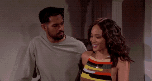 a man and a woman are standing next to each other and the woman is wearing a pink dress