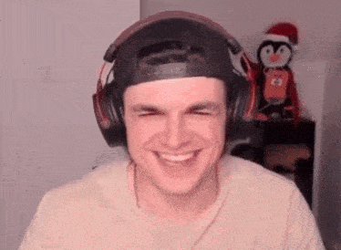 a young man wearing headphones and a baseball cap is smiling .