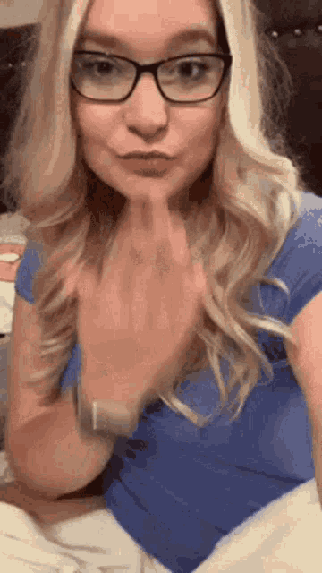 a woman wearing glasses and a blue shirt is making a face .