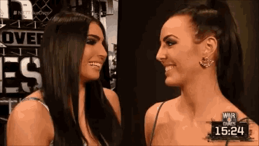 two women are smiling and looking at each other in front of a sign that says over