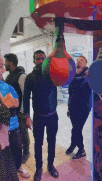 a man is standing in front of a punching bag that has the letter b on the side