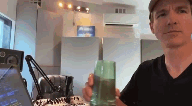 a man holds a glass of water in front of a microphone