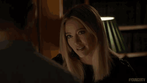 a woman is talking to a man in a dark room .