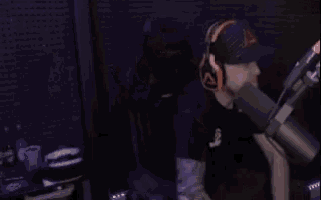 a man wearing headphones and a baseball cap is sitting in front of a microphone .